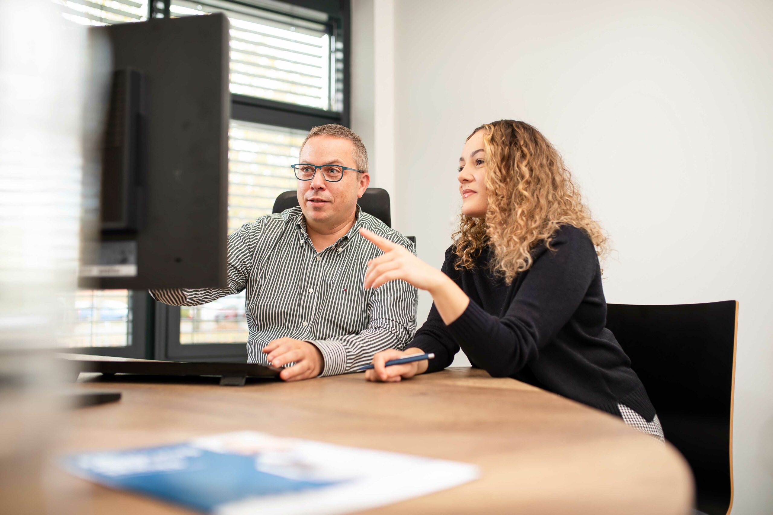 Zwei Mitarbeitenden besprechen etwas am PC